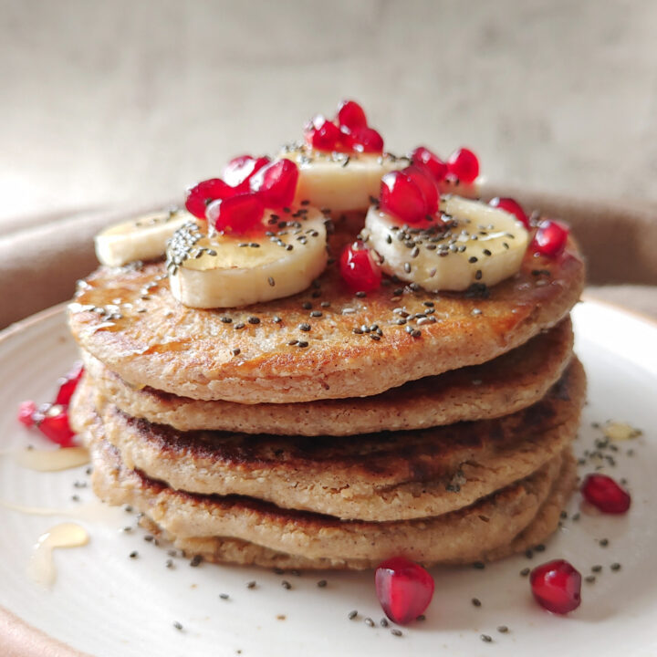 featured image of oat banana pancakes stacked with toppings in a plate
