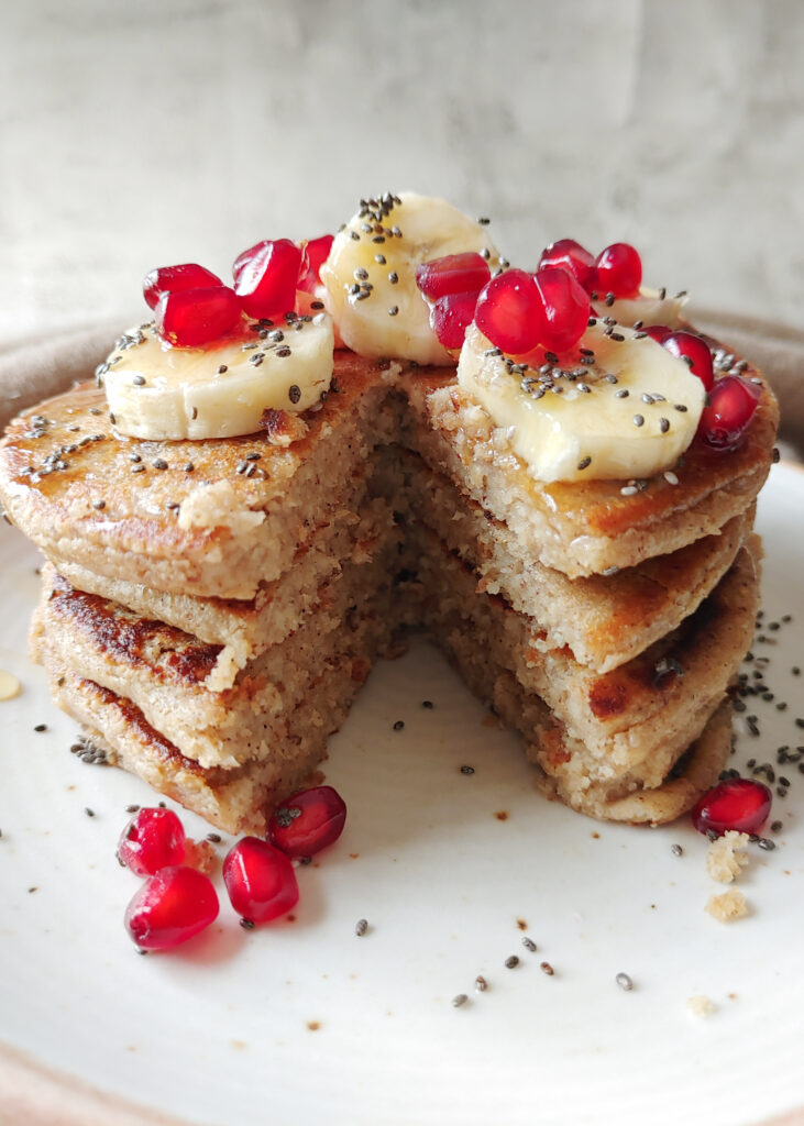sliced oat banana pancakes  stacked with toppings in a plate
