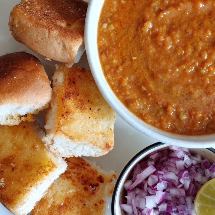 close look of pav bhaji served on a plate with onions and lemon wedges