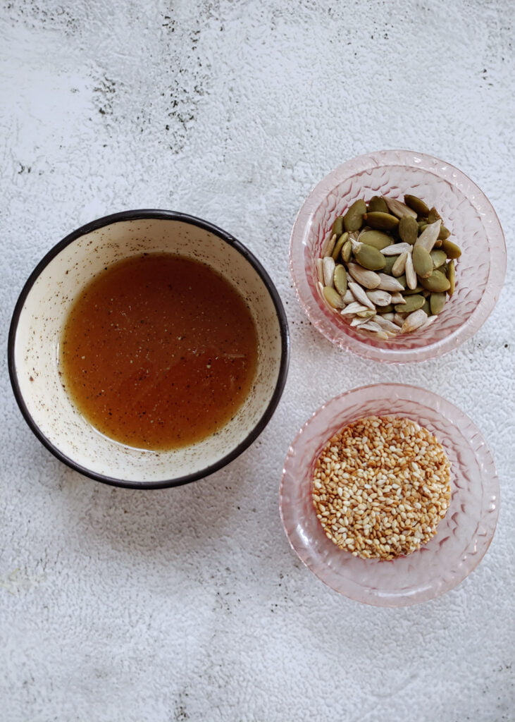 salad dressing, toasted sesame seeds, roasted sunflower and pumpkin seeds in separate bowls