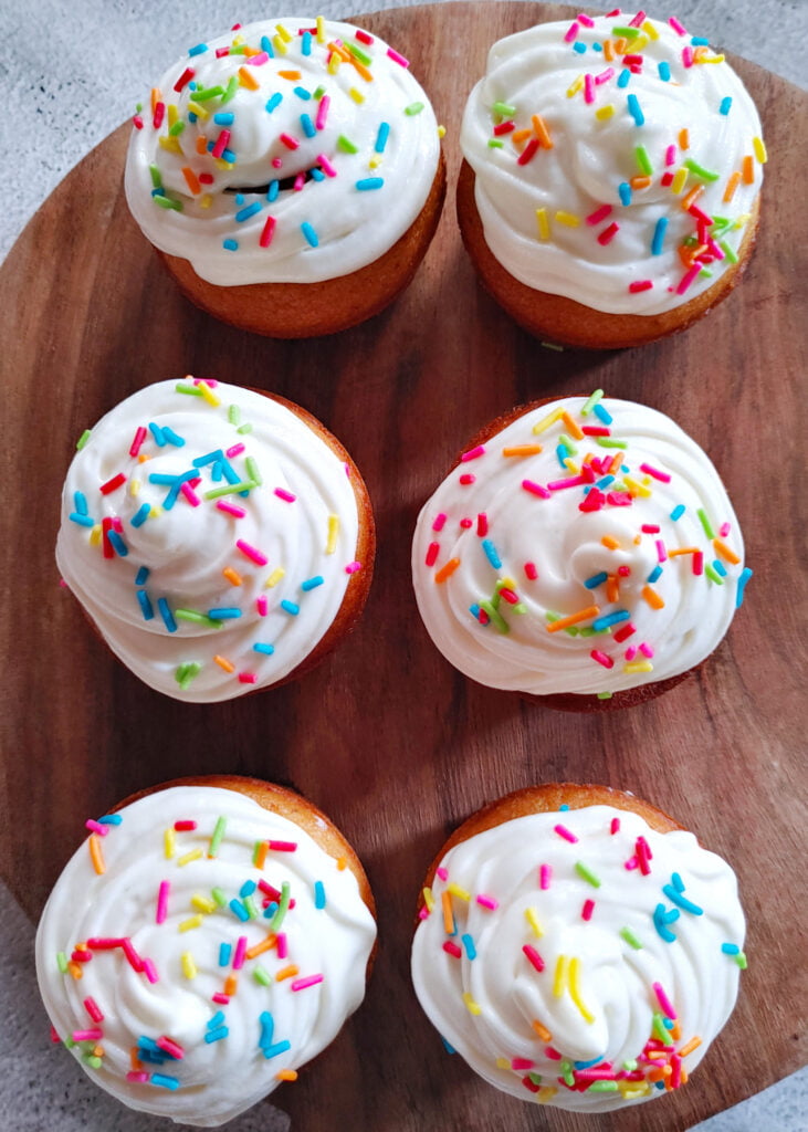 eggless vanilla cupcake with buttercream frosting and rainbow sprinkles placed on a platter