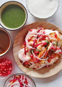featured image of aloo tikki chaat served in a plate with sauces , curd and garnishes on the side
