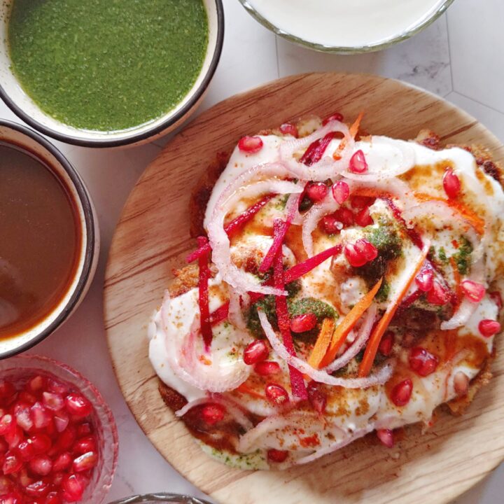 featured image of aloo tikki chaat served in a plate with sauces , curd and garnishes on the side