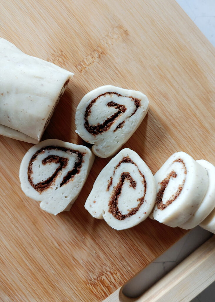 cinnamon roll cookies dough in log shape with cinnamon and brown sugar filling cut into pieces