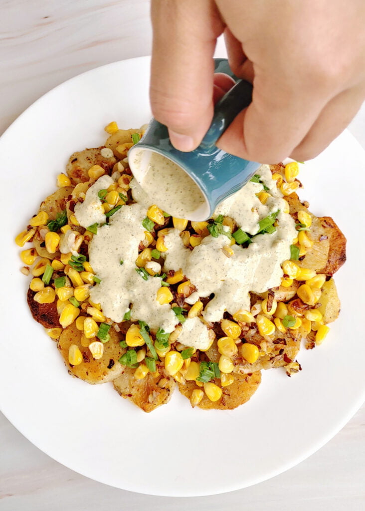 pumpkin seed dressing poured over roasted potatoes and corn salad