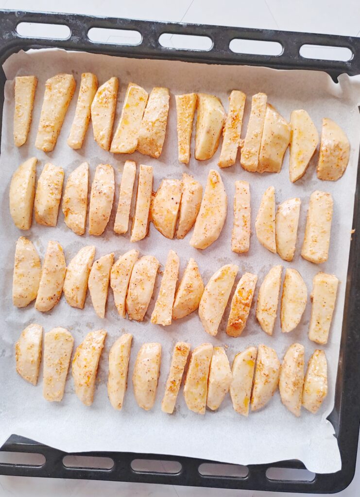 lengthwise sliced potatoes placed in a baking tray before baking