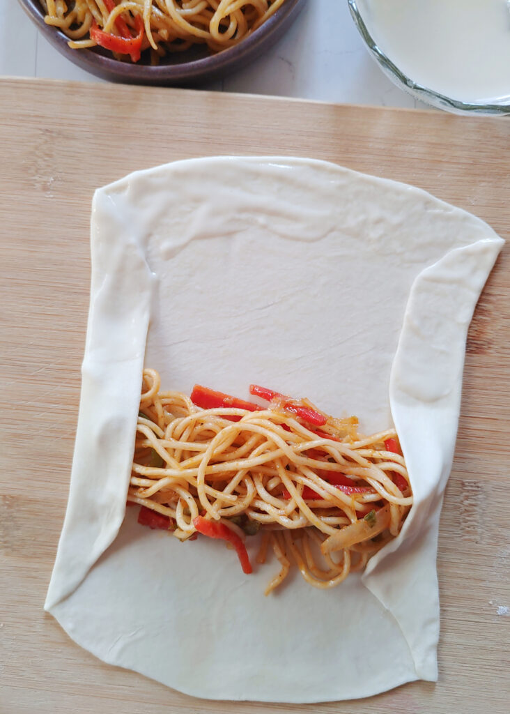 veggie noodles added to a spring roll sheet and sheet folded from the sides