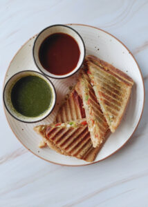 featured image of potato veg grilled sandwich served in a plate along with sweet tamarind and mint coriander chutneys