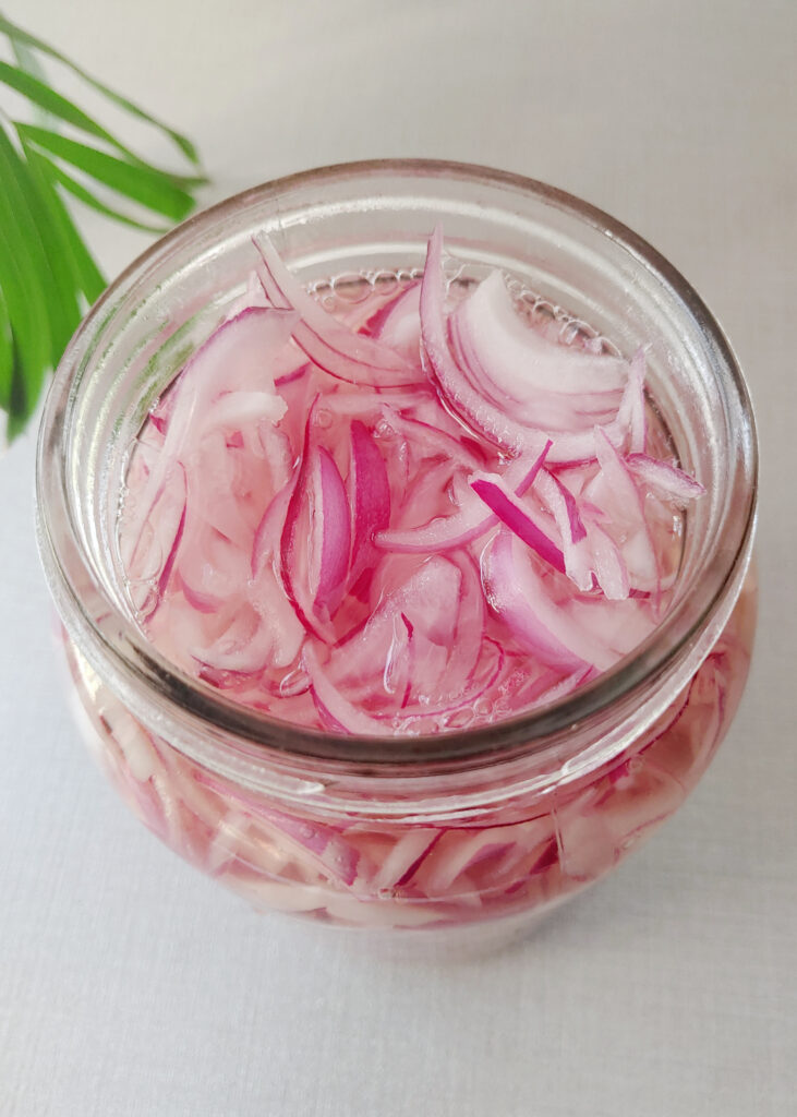 photo taken from top of sliced onions soaked in vinegar solution in a glass jar