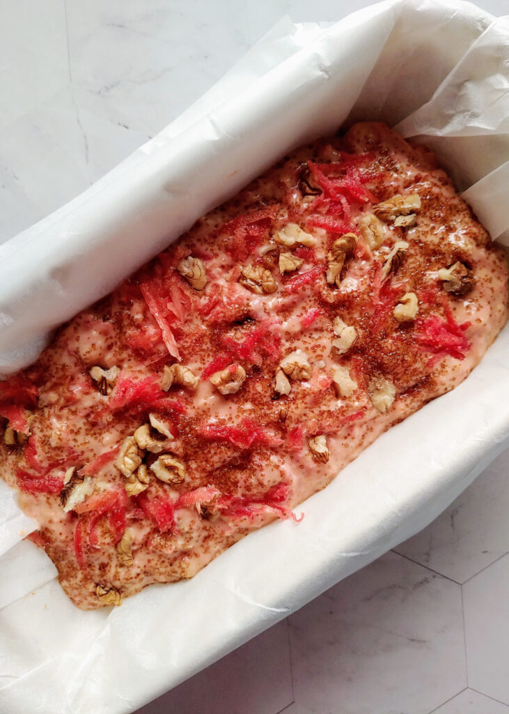 eggless carrot walnut bread batter spread in a loaf tin